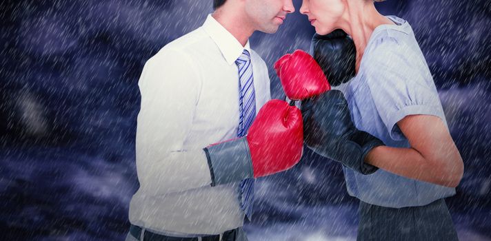 Business people wearing and boxing red gloves against gloomy sky