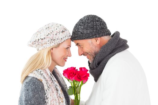 Smiling couple in winter fashion posing with roses on white background