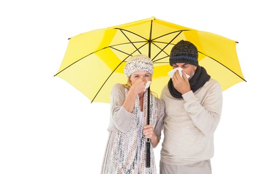 Couple in winter fashion sneezing under umbrella on white background