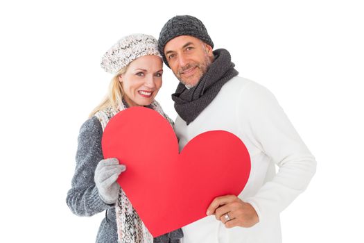Smiling couple in winter fashion posing with heart shape on white background