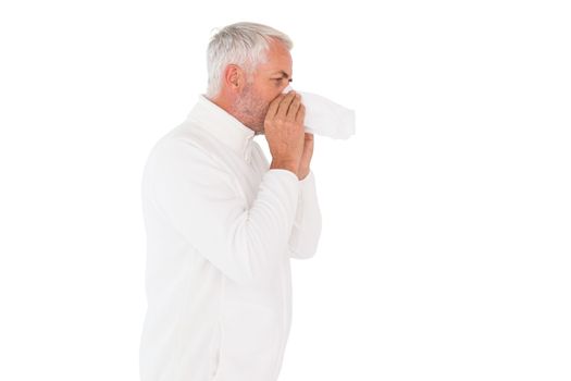 Sick man in winter fashion sneezing on white background