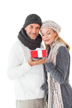Smiling couple in winter fashion holding present on white background