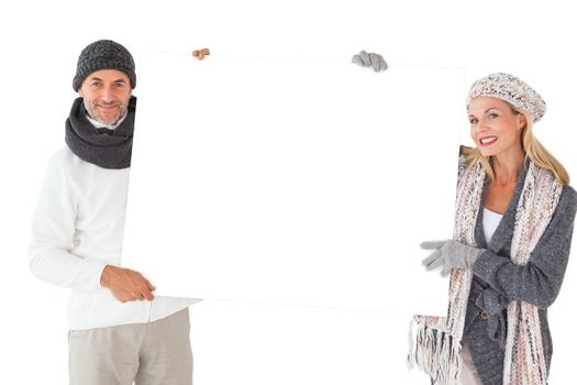 Smiling couple in winter fashion holding poster on white background