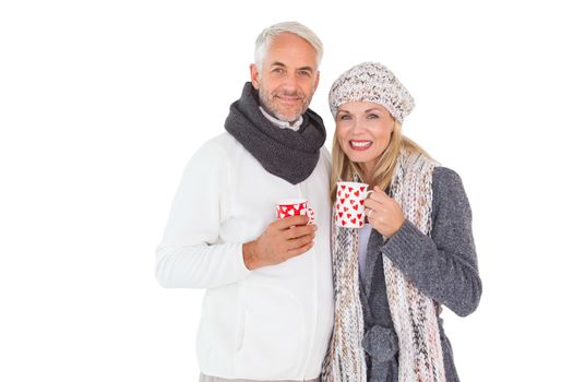 Happy couple in winter fashion holding mugs on white background