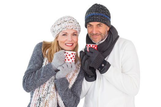 Happy couple in winter fashion holding mugs on white background