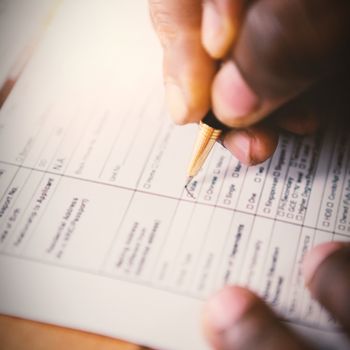 Close-up of man hands signing insurance document at desk