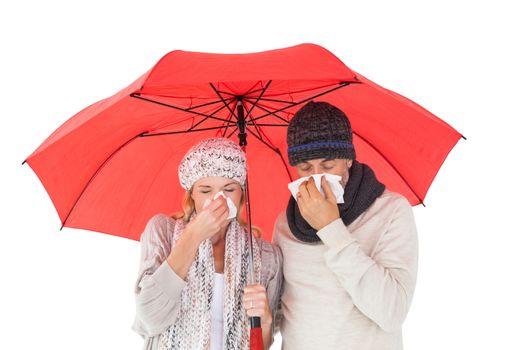 Couple in winter fashion sneezing under umbrella on white background