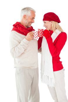 Smiling couple in winter fashion toasting with mugs on white background