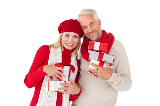 Smiling couple in winter fashion holding presents on white background