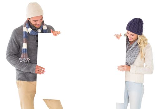 Attractive couple in winter fashion showing poster on white background