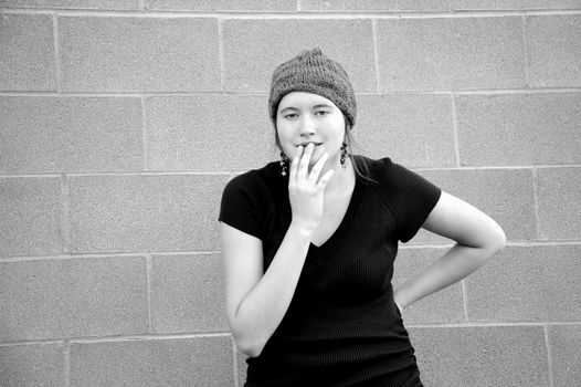 Female tomboy posing against a wall outside.