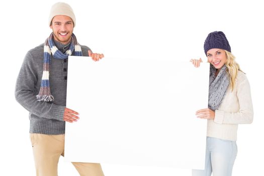 Attractive couple in winter fashion showing poster on white background