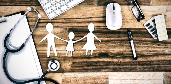 Paper cut out family chain with various medical equipment and keyboard on table