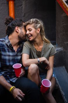 Romantic couple enjoying while having drink on staircase of bar
