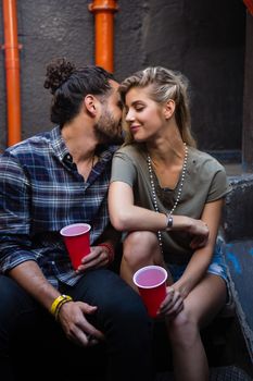 Romantic couple enjoying while having drink on staircase of bar