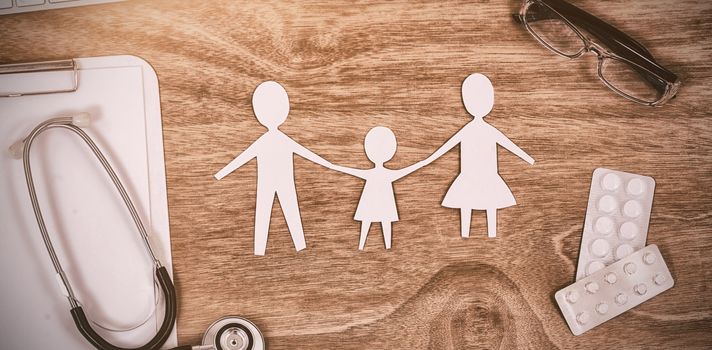 Various medical equipment with keyboard and paper cut out family chain on wooden table