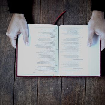 Woman holding bible on wooden table