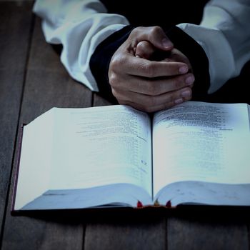 Cropped hands of woman by bible at table