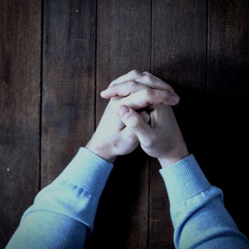 Cropped image of man praying on wooden table