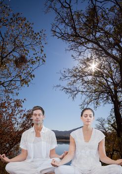 Digital composite of Woman and man doing yoga in front of a lake and mountains