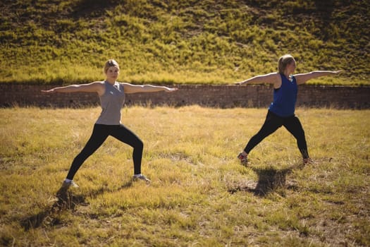 Beautiful women praising yoga during obstacle course in boot camp