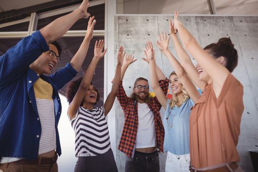 Cheerful business people with arms raised in creative office