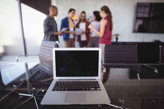 High angle view of laptop on table with business people in background