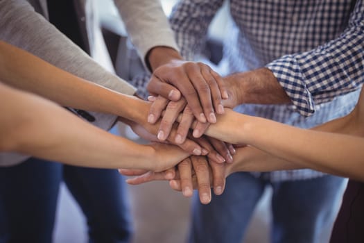 Close up business people stacking hands at creative office