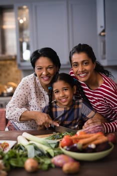 Portrait of smiling multi-generation family preparing food together in kitchen at home