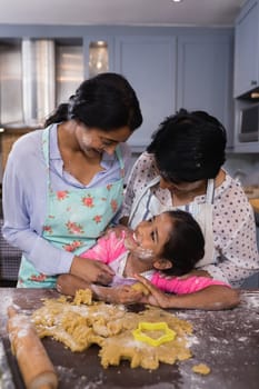 Smiling multi-generation family standing by dough in kitchen at home