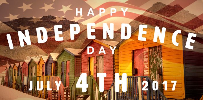 Happy 4th of july text on white background against multi colored wooden huts by mountain at beach