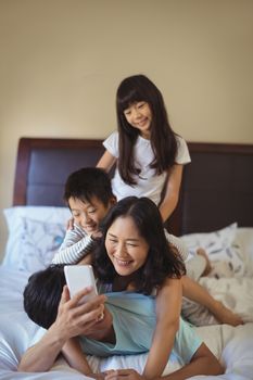 Happy family using mobile phone in the bed room at home