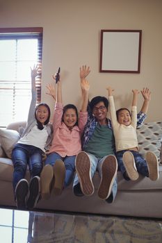Smiling family watching television together in living room at home