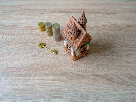 Model of a house, Stack of European Euro coins and golden key On Wooden Table. Real estate agency, mortgage loan, lottery, buying property.Home loan and investment concept. Copy space