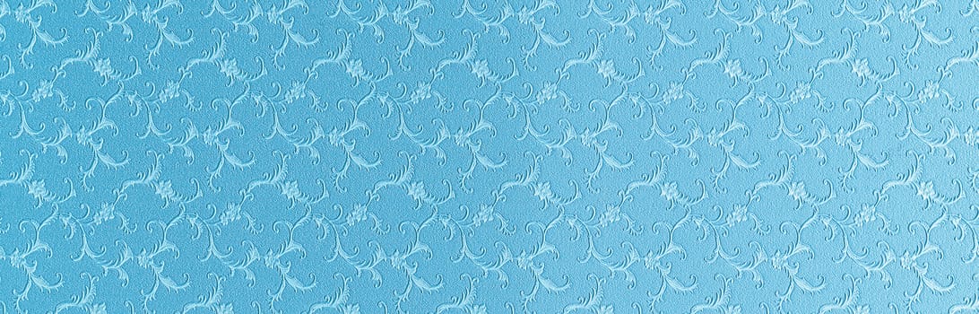 Embossed floral pattern on blue paper. Textured paper with copy space. Light blue paper surface, texture closeup.