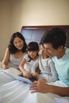 Family using laptop together in bedroom at home