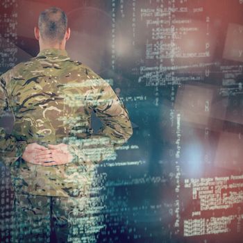 Rear view of soldier standing with his hands behind back against abstract black room