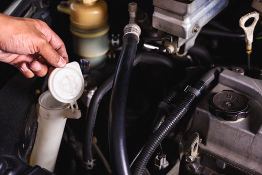 Hand of Mechanic technician service check level water on wiper lid can in garage