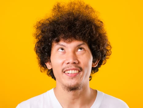 Asian handsome man with curly hair looking up see he hair isolate on yellow background with copy space for text