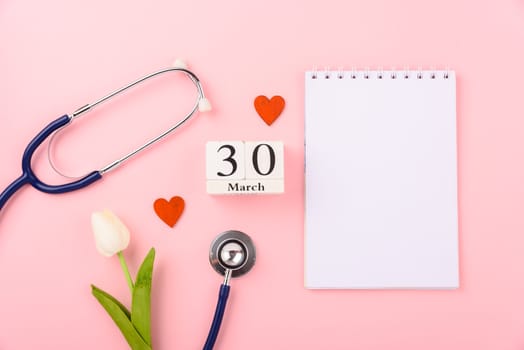 Doctor's Day concept, flat lay top view, equipment medical red heart stethoscope and note book on pink background, care patient in hospital with copy space for text