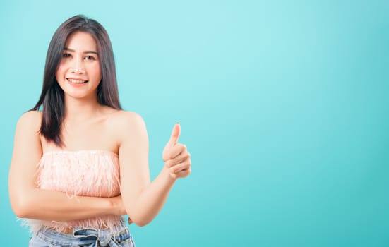 Portrait asian beautiful woman smiling her showing thumbs up and looking to camera on blue background, with copy space for text
