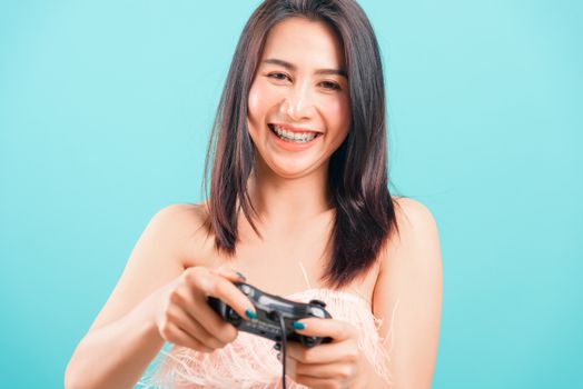 Smiling face portrait asian beautiful woman her playing video games by joy on blue background, with copy space for text
