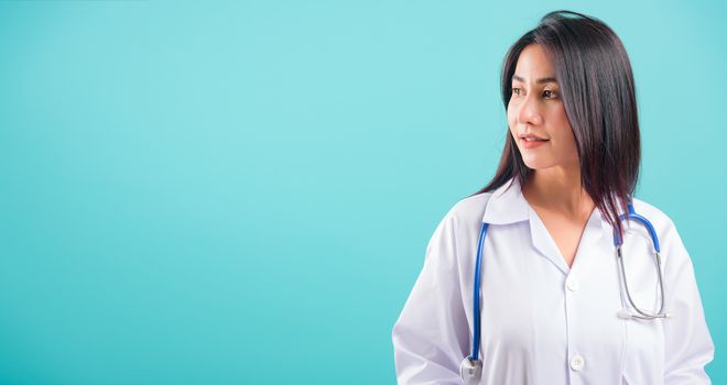 Portrait asian beautiful doctor woman smiling her standing with Hands in Pockets on blue background, with copy space for text