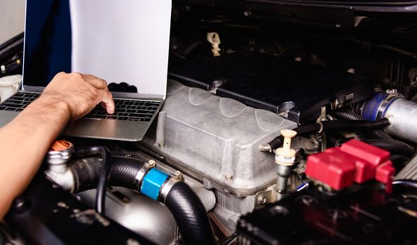 Professional car repair or maintenance mechanic engine working service with laptop computer at workshop