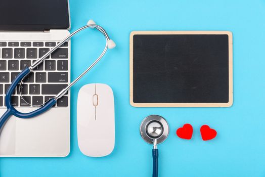 Doctor's Day concept, flat lay top view, stethoscope with laptop computer and black board diagnosis of heart disease on blue background with copy space for text