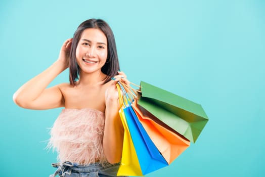 Portrait asian beautiful woman happy smiling her holding shopping bags on blue background, with copy space for text