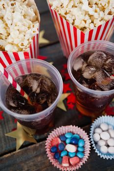 Popcorn, confectionery and drink arranged on wooden table