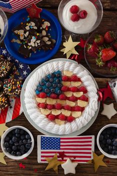 Fruitcake and various sweet foods arranged on wooden table with 4th July theme