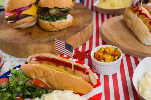 Close-up of burgers and hot dogs on wooden table with 4th july theme