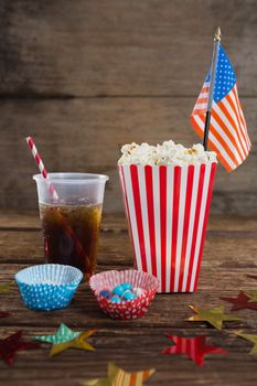 Popcorn, sweet food and cold drink decorated with 4th july theme on wooden table